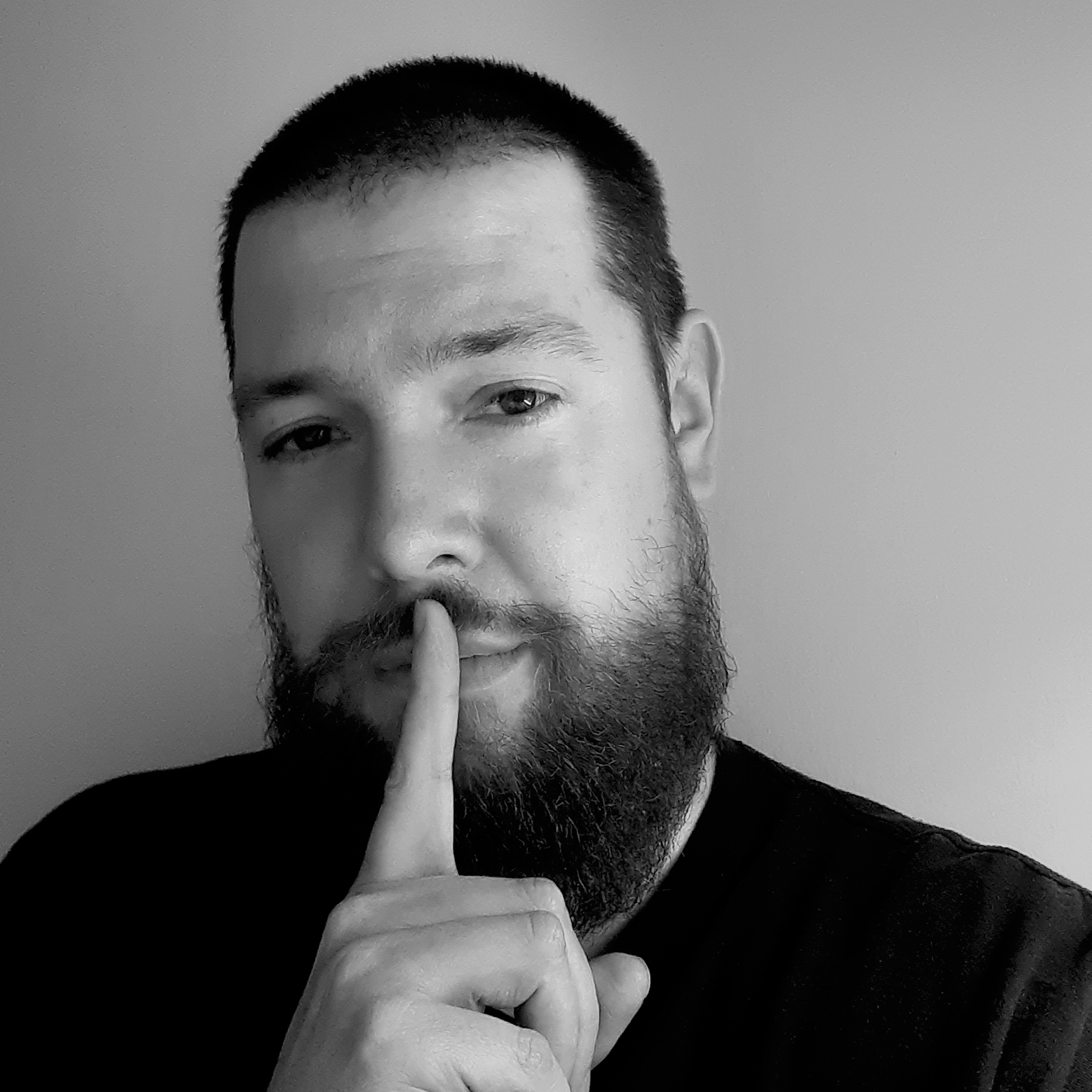 Black and white portrait of Snows with a finger raised to their lips
